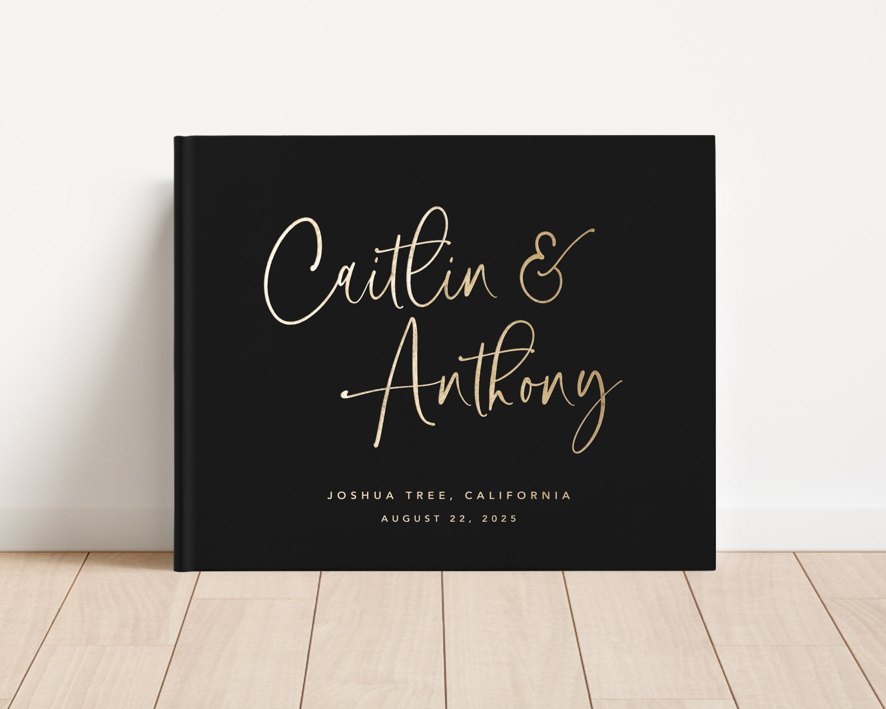 Luxury wedding guest book with custom gold foil text and black hardback cover.